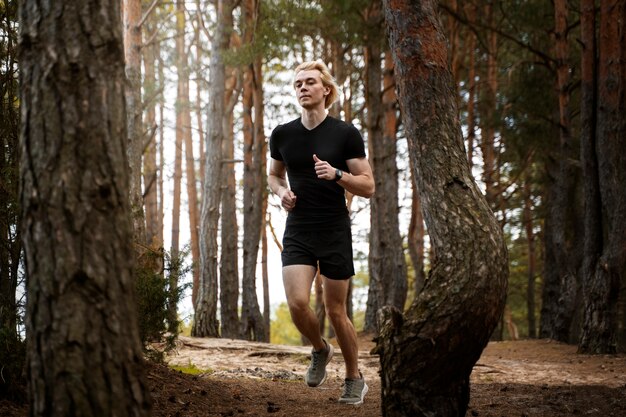 Hombre de tiro completo corriendo en el bosque