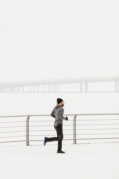 Hombre de tiro completo corriendo en la nieve