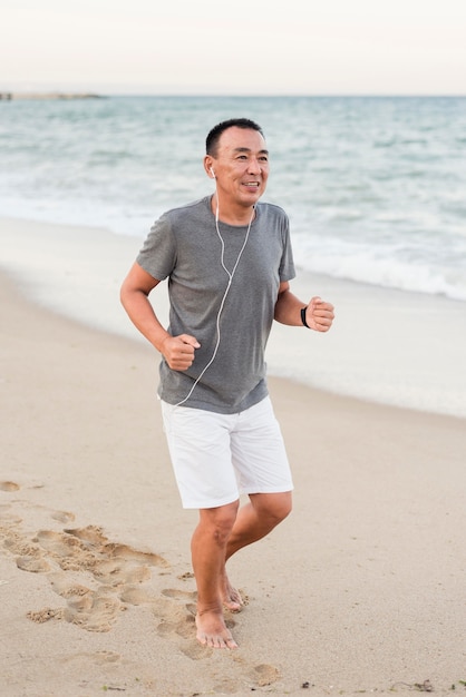 Hombre de tiro completo corriendo en la playa