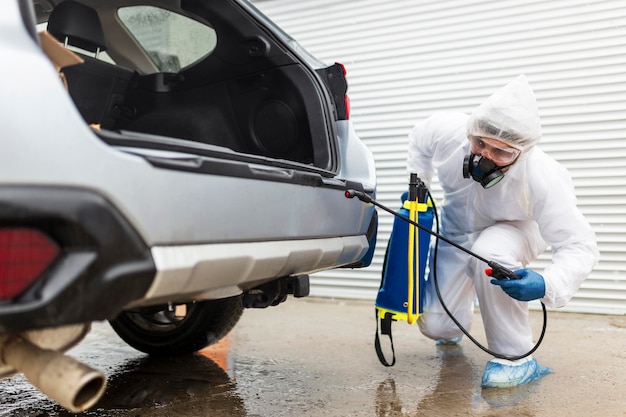 Hombre de tiro completo desinfectando el coche