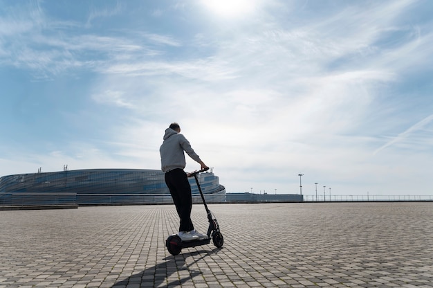 Hombre de tiro completo divirtiéndose con scooter eléctrico