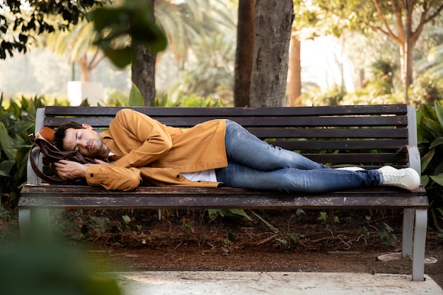 Hombre de tiro completo durmiendo en un banco