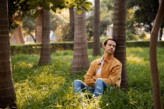 Hombre de tiro completo durmiendo cerca del árbol