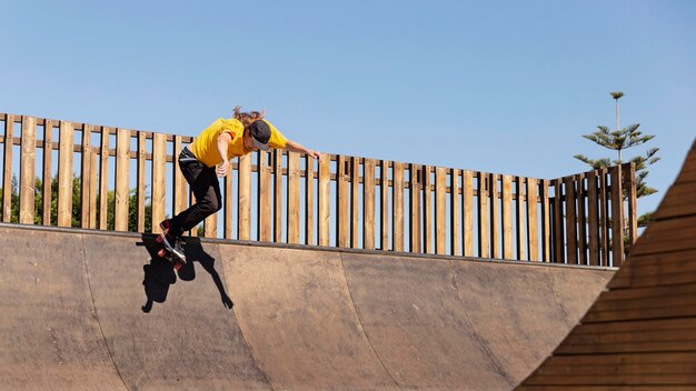 Hombre de tiro completo entrenando con patineta