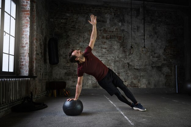 Hombre de tiro completo entrenando con pelota de gimnasia