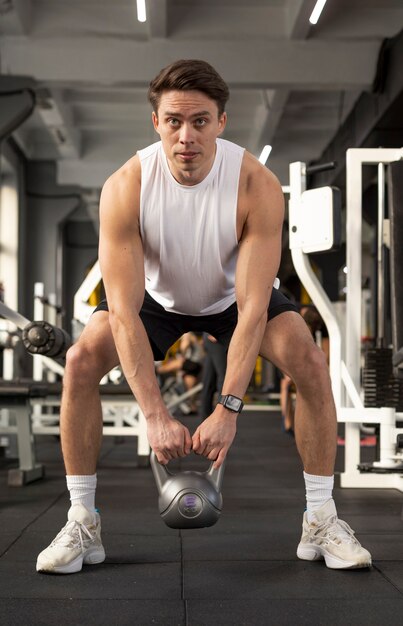 Hombre de tiro completo entrenando con pesas rusas