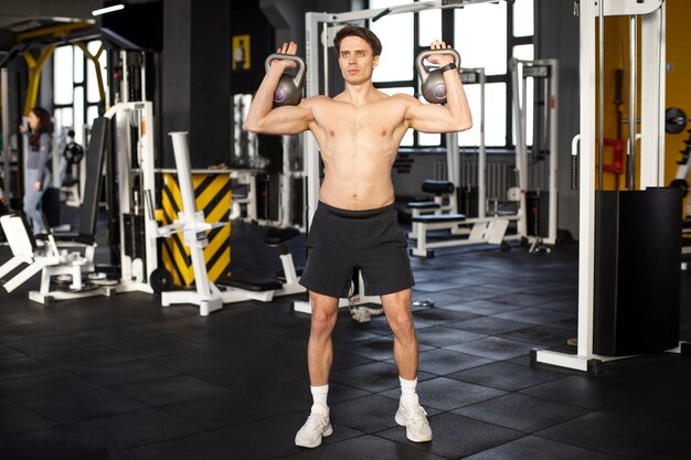 Hombre de tiro completo entrenando con pesas rusas