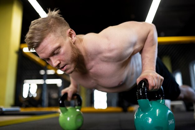 Hombre de tiro completo entrenando con pesas rusas