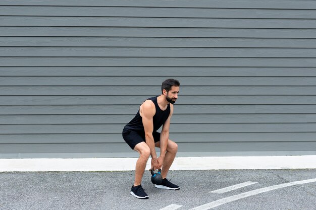 Hombre de tiro completo entrenando con pesas rusas