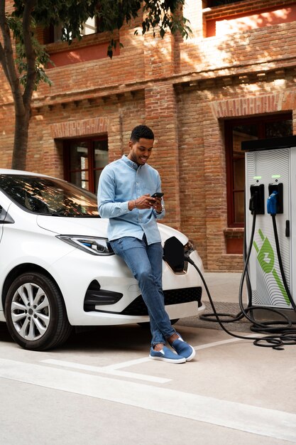 Hombre de tiro completo esperando que se cargue el coche eléctrico