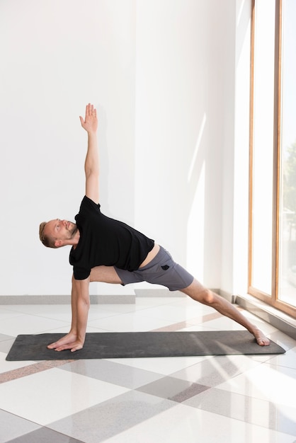 Hombre de tiro completo en la estera practicando yoga pose