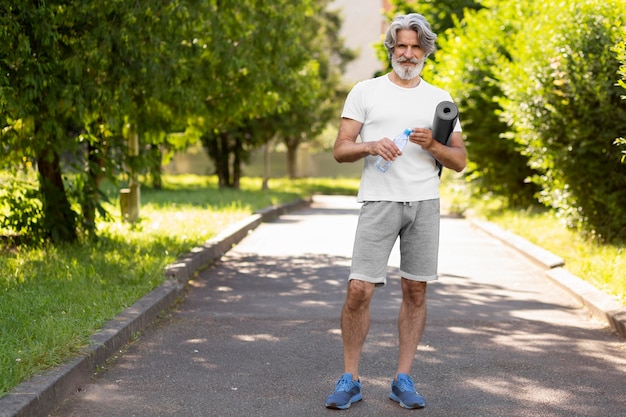 Hombre de tiro completo con estera de yoga