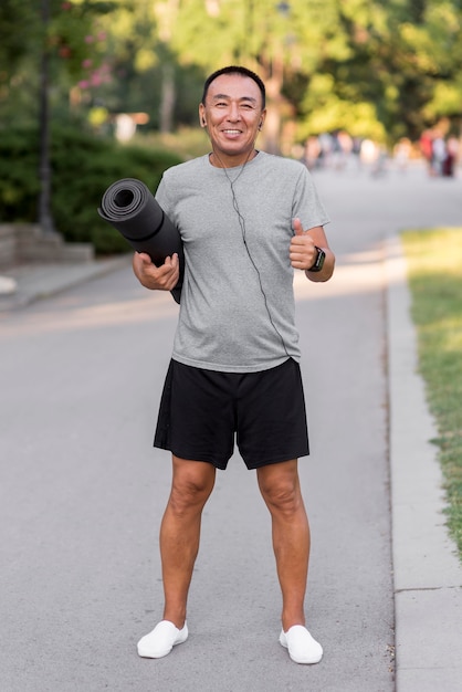 Hombre de tiro completo con estera de yoga