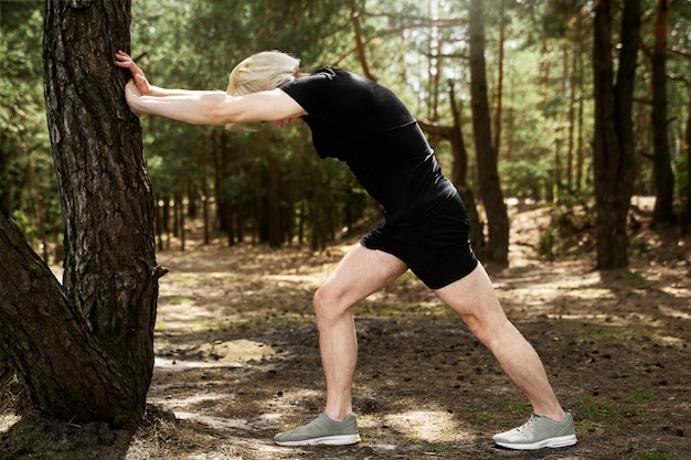 Hombre de tiro completo estirando con árbol