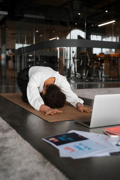 Hombre de tiro completo estirándose en el trabajo