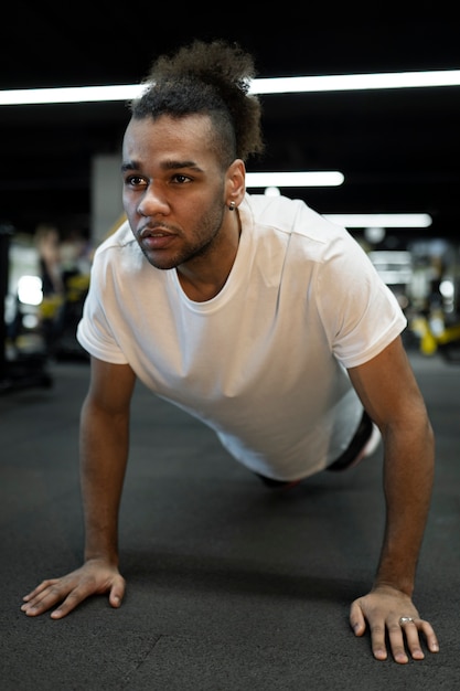 Hombre de tiro completo haciendo burpee en el gimnasio