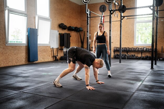 Hombre de tiro completo haciendo burpees en el gimnasio