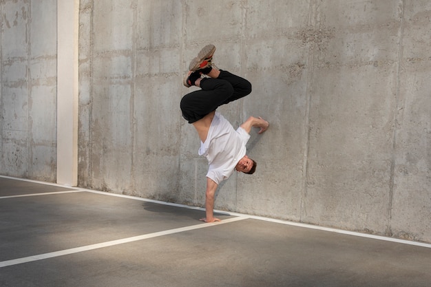 Hombre de tiro completo haciendo entrenamiento de parkour al aire libre