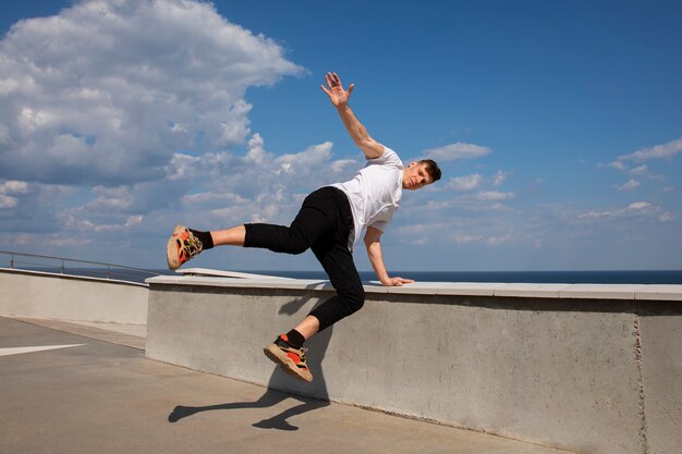 Hombre de tiro completo haciendo entrenamiento de parkour al aire libre