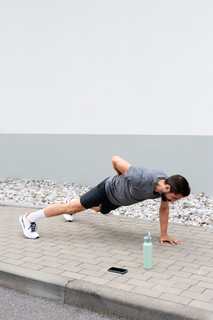 Foto gratuita hombre de tiro completo haciendo flexiones al aire libre