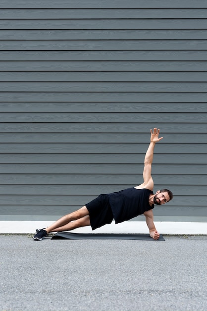 Hombre de tiro completo haciendo plancha lateral