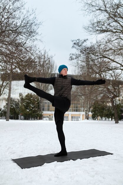 Hombre de tiro completo haciendo yoga en clima frío