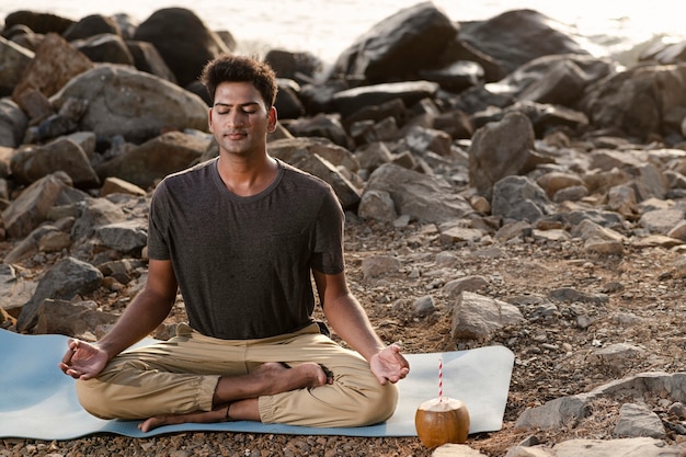 Hombre de tiro completo haciendo yoga en la estera