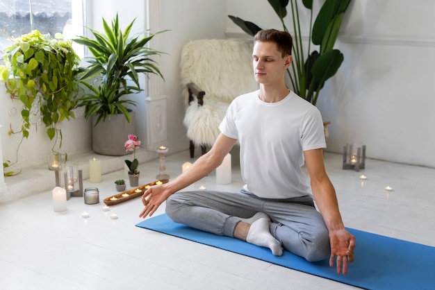 Hombre de tiro completo haciendo yoga en la estera