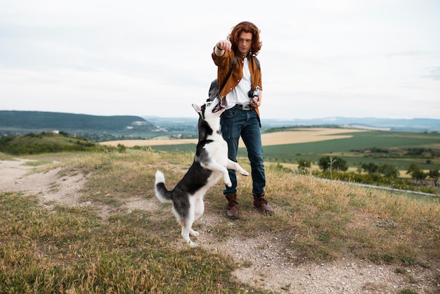 Foto gratuita hombre de tiro completo con husky fuera