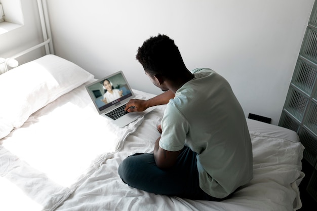 Hombre de tiro completo con laptop en la cama