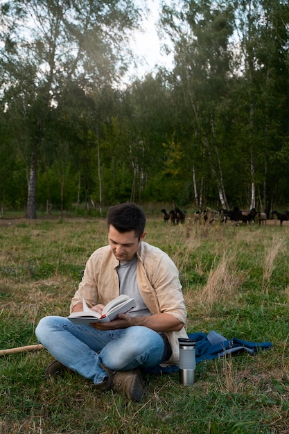 Hombre de tiro completo leyendo al aire libre