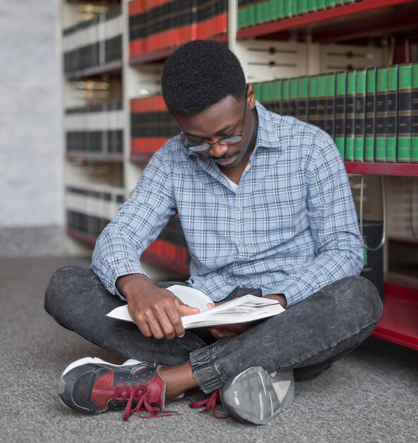 Hombre de tiro completo leyendo en el piso