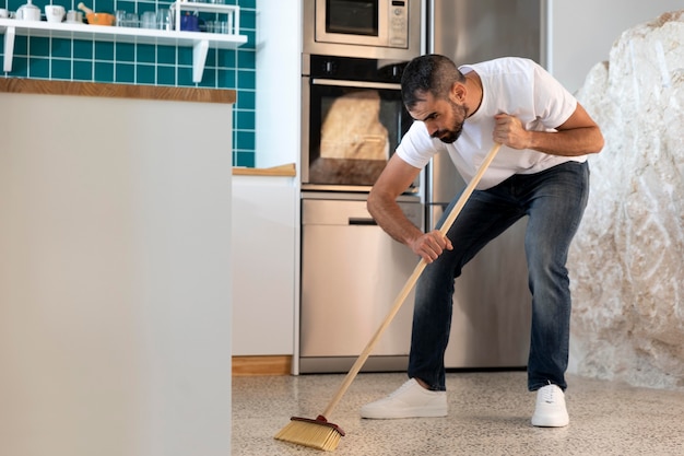 Hombre de tiro completo limpiando la cocina