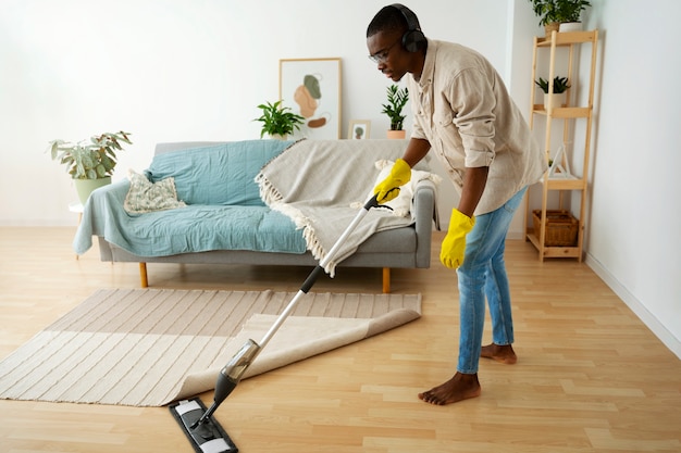 Foto gratuita hombre de tiro completo limpiando piso con trapeador