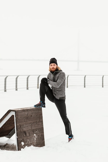 Hombre de tiro completo en la nieve que se extiende