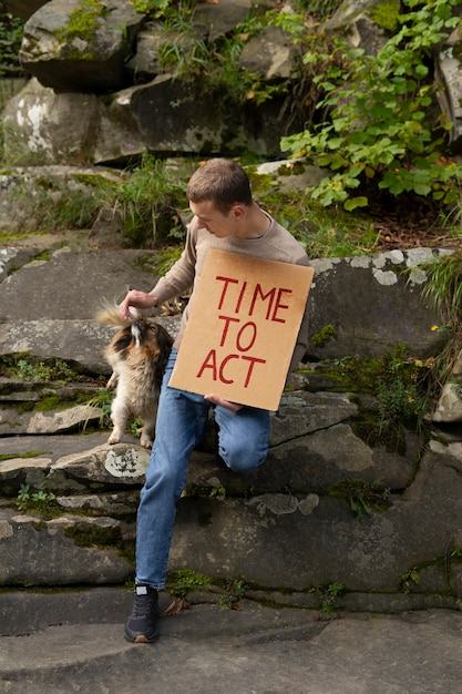 Foto gratuita hombre de tiro completo con pancarta y perro.