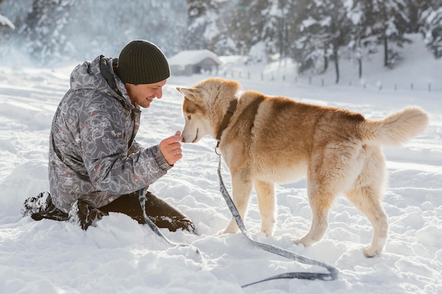 Hombre de tiro completo con perro en la nieve