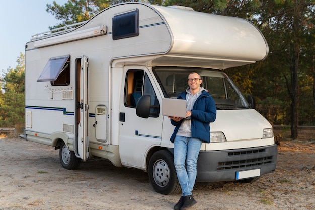 Hombre de tiro completo de pie cerca de autocaravana