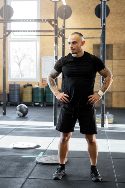 Hombre de tiro completo de pie en el gimnasio