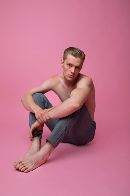 Hombre de tiro completo posando con fondo rosa