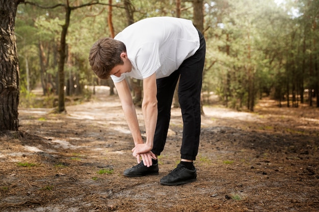 Hombre de tiro completo que se extiende en la naturaleza