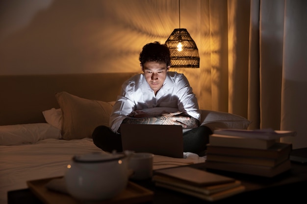 Hombre de tiro completo que trabaja en la computadora portátil en casa