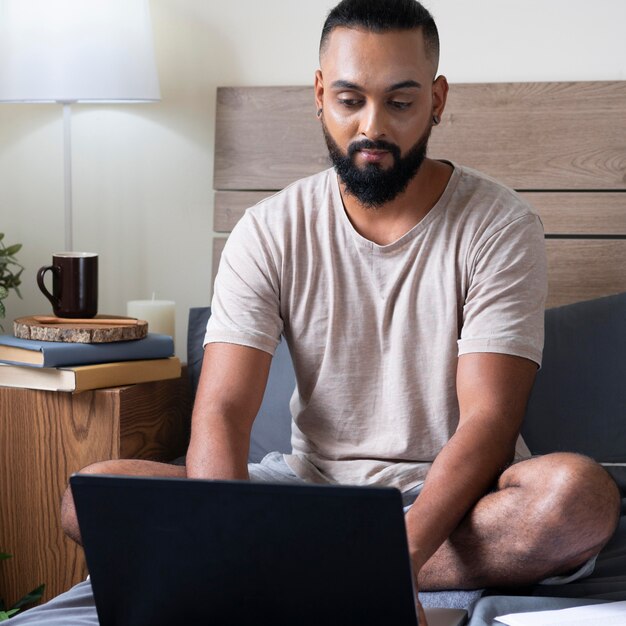 Hombre de tiro completo que trabaja en el dormitorio