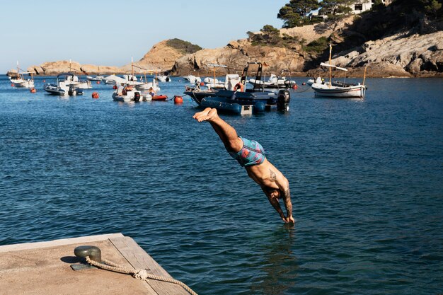 Hombre de tiro completo saltando en el agua