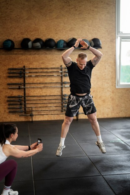 Hombre de tiro completo saltando en el gimnasio