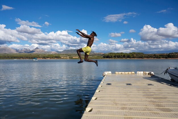 Hombre de tiro completo saltando en el lago