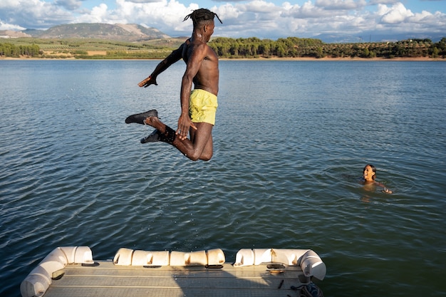 Hombre de tiro completo saltando en el lago