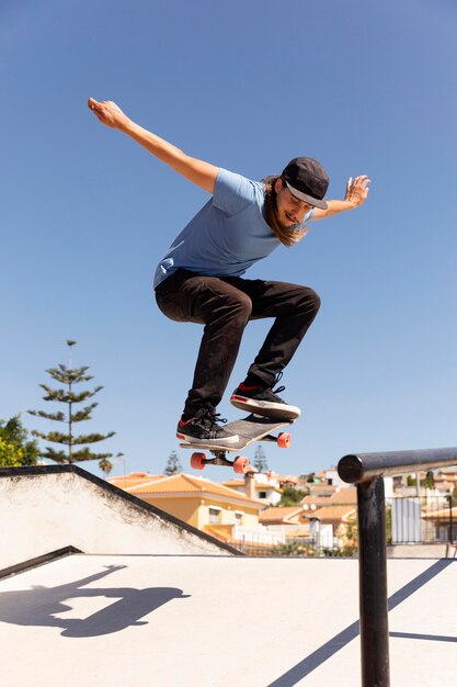 Hombre de tiro completo saltando con patineta