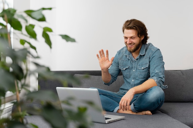 Hombre de tiro completo saludando a la computadora portátil