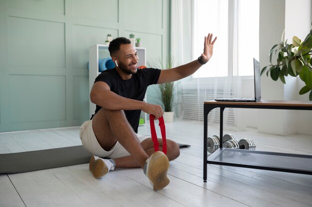 Hombre de tiro completo saludando a la computadora portátil